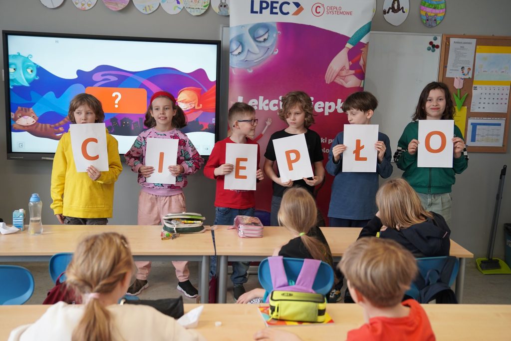 Dzieci uczestniczą w zajęciach edukacyjnych LPEC, prezentując litery układające się w słowo „CIEPŁO”.