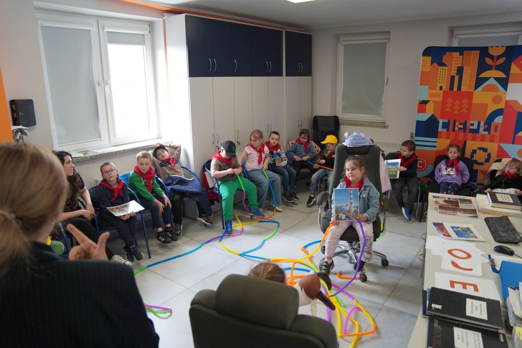 Grupa dzieci bierze udział w warsztatach edukacyjnych LPEC, poznając zasady działania systemu ciepłowniczego poprzez wspólne zajęcia