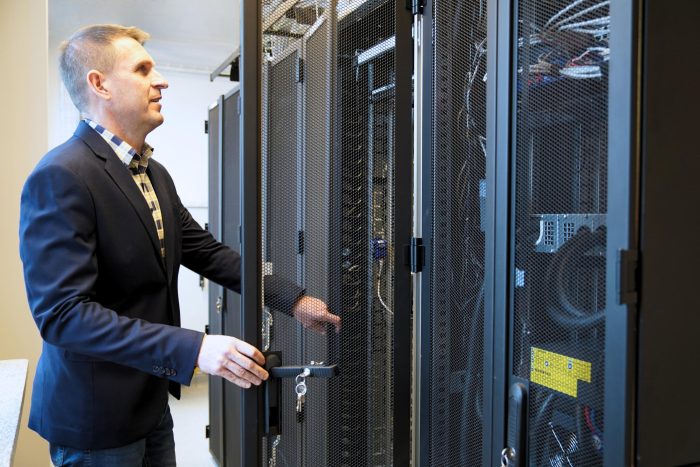 Pracownik LPEC obsługuje szafę serwerową w centrum infrastruktury informatycznej przedsiębiorstwa.